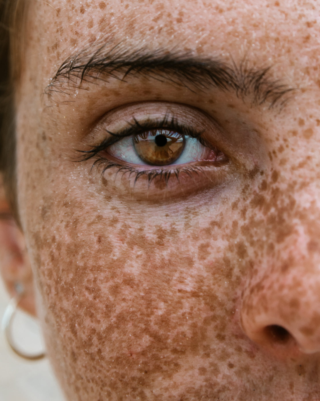 Primo piano del contorno occhi di un viso femminile naturale con lentiggini