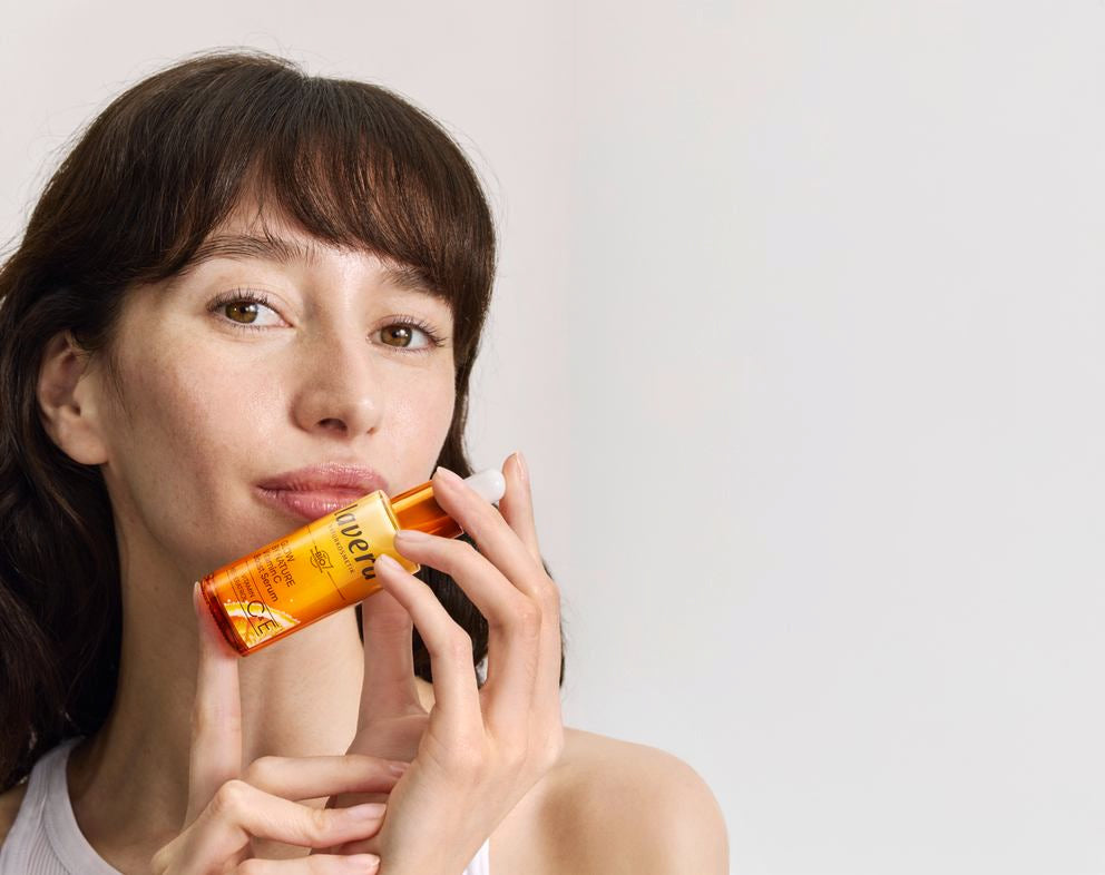Frau hält lavera Serum an die Wange im Studio