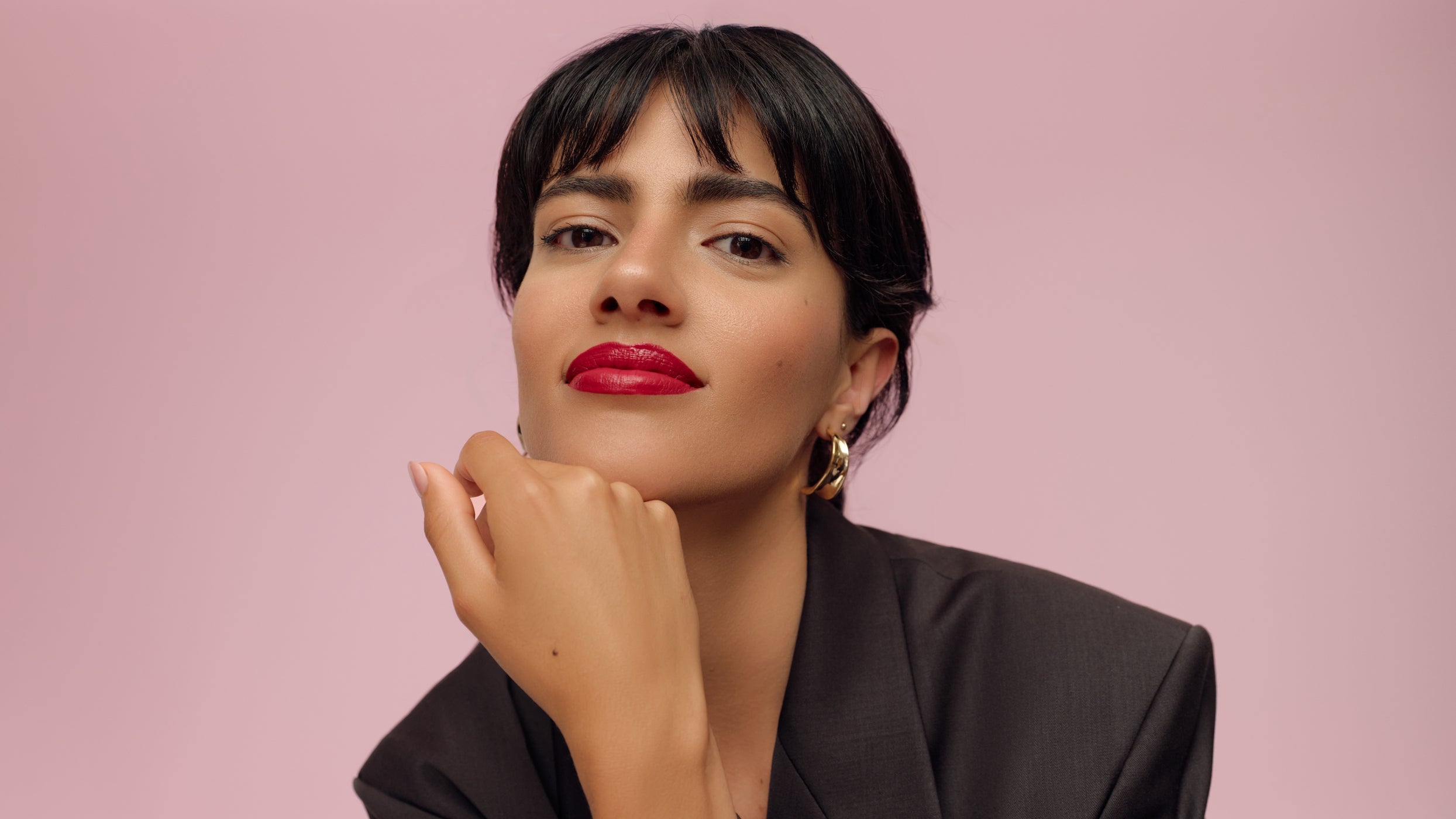 Ritratto: donna con rossetto rosso su sfondo rosa, look elegante
