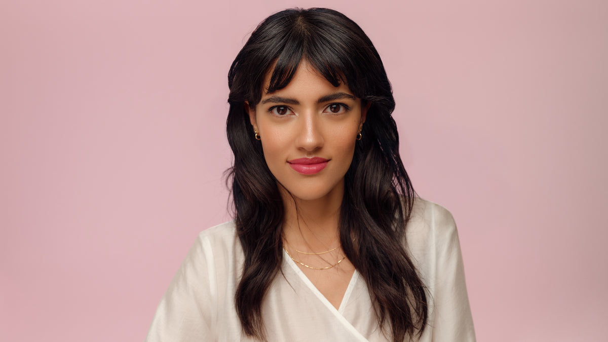 Giovane donna con capelli castano scuro, occhi marroni e look make-up elegante