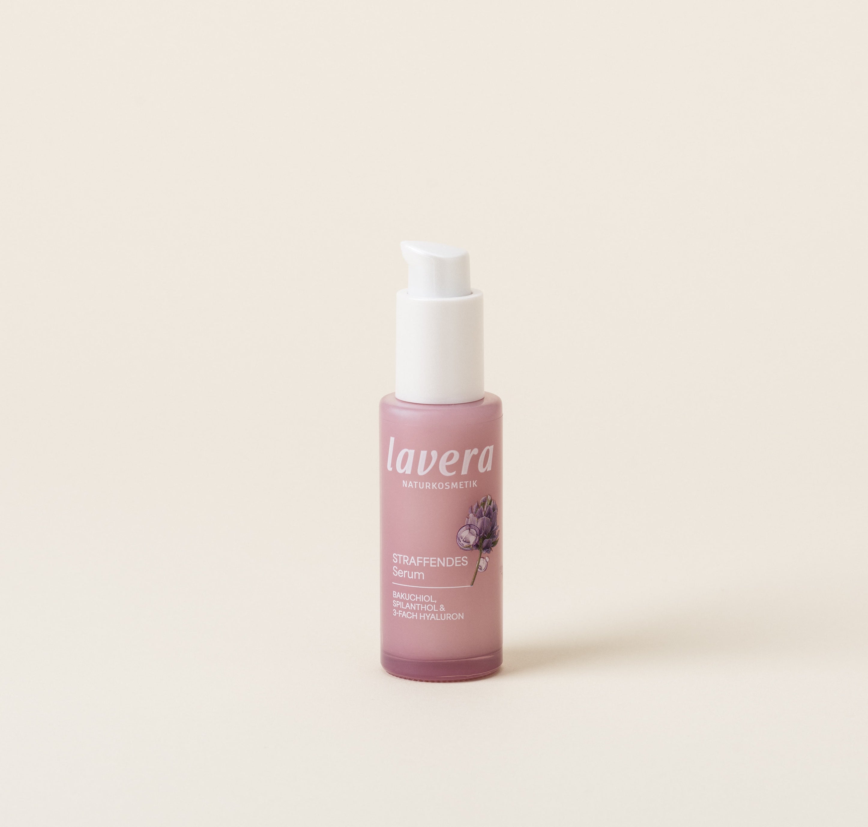 Eine rosafarbene Flasche lavera Straffendes Serum steht vor einem hellen, neutralen Hintergrund.