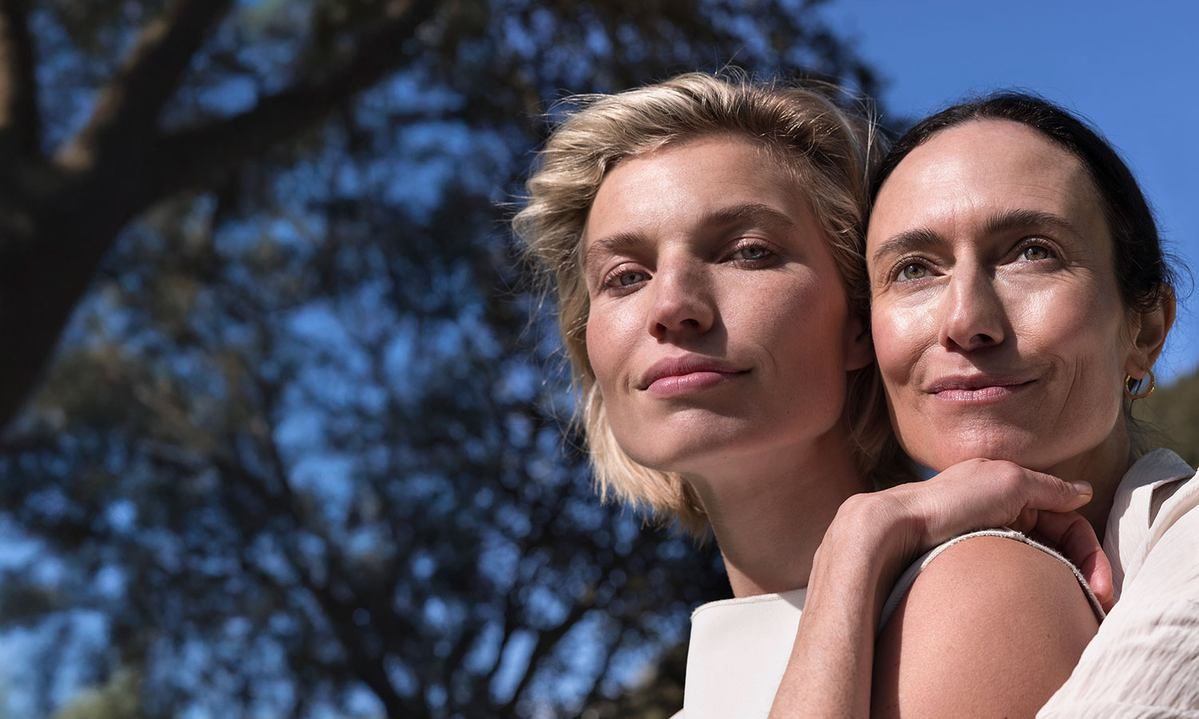 Due donne al sole, una abbraccia l'altra, look naturale all'aperto