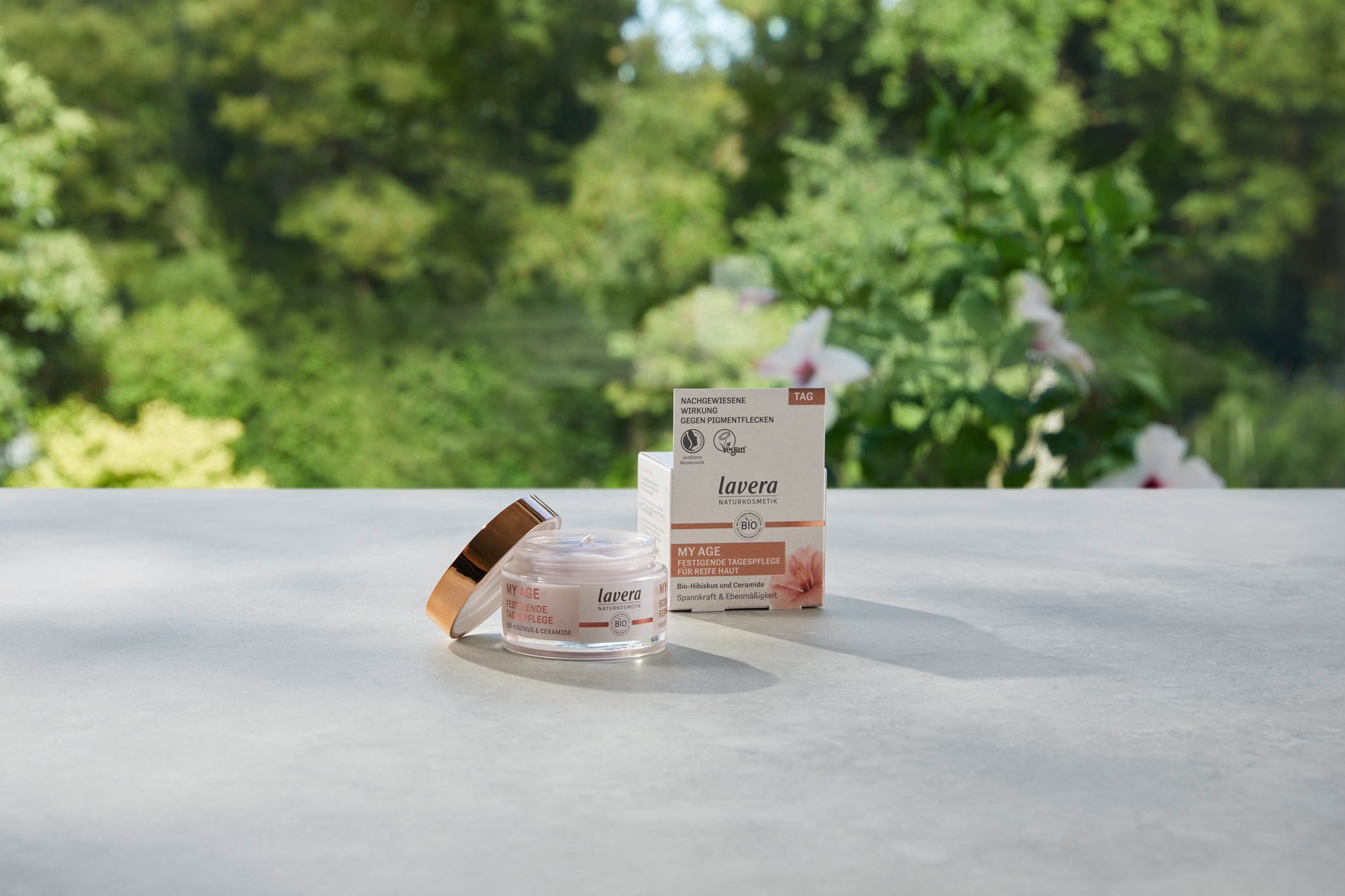 Lavera My Age festigende Tagespflege für reife Haut mit Bio-Hibiskus, Produktfoto im Grünen.