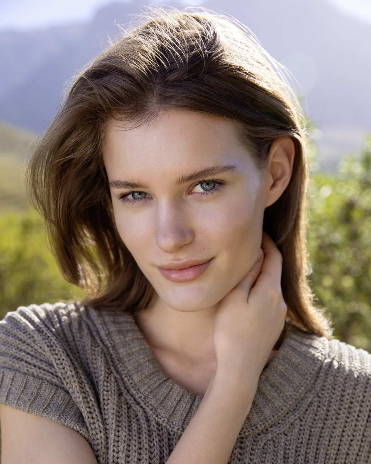 Donna castana all'aperto con un look naturale sullo sfondo delle montagne