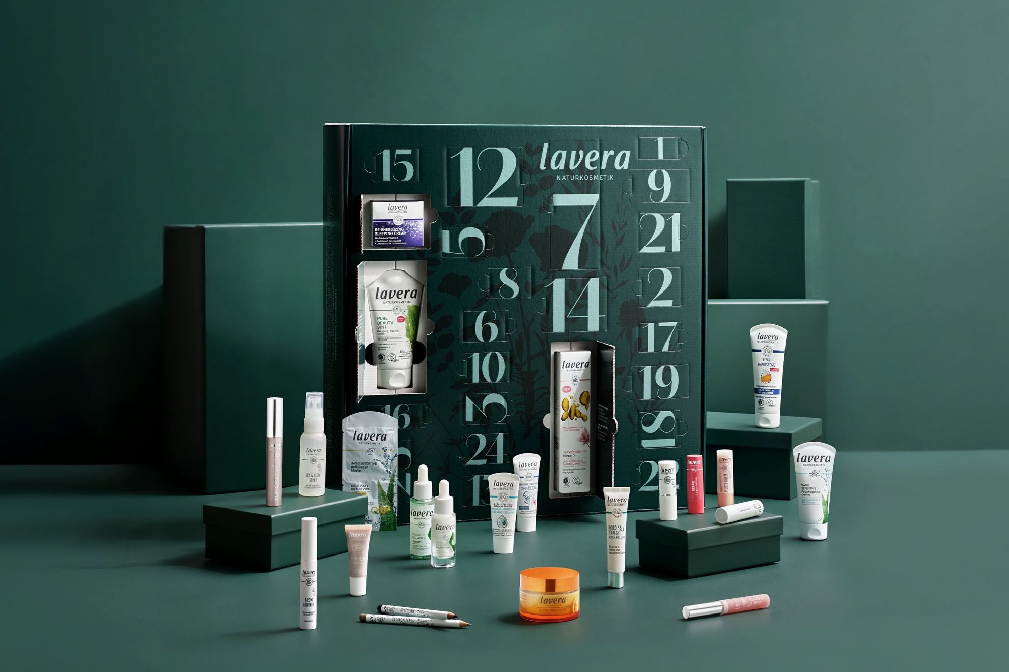 Calendario dell'Avvento lavera aperto con mini prodotti di cura e make-up su set verde