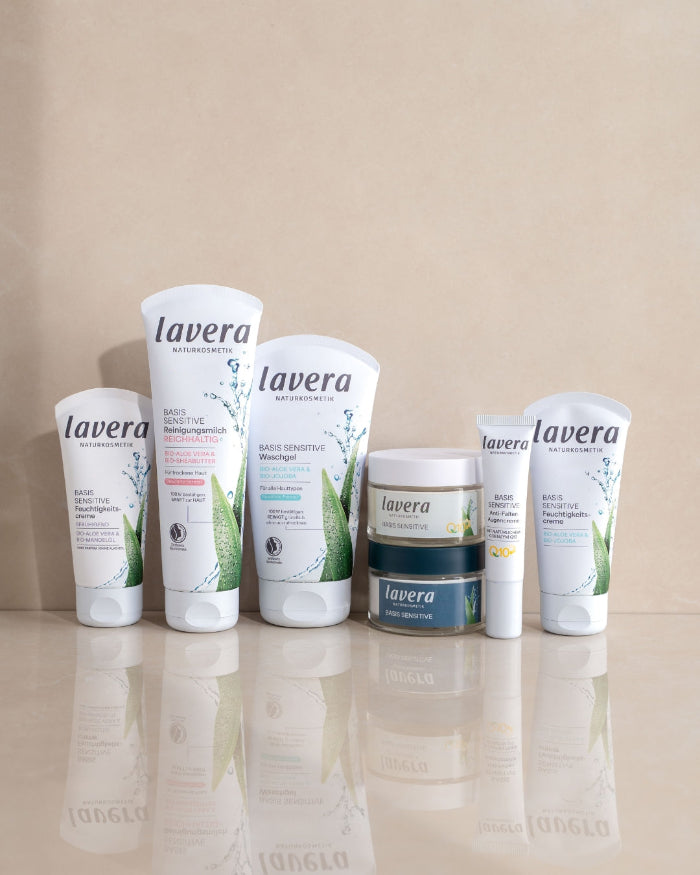 Diversi prodotti lavera BASIS SENSITIVE per la cura del viso sono disposti uno accanto all’altro su una superficie riflettente.