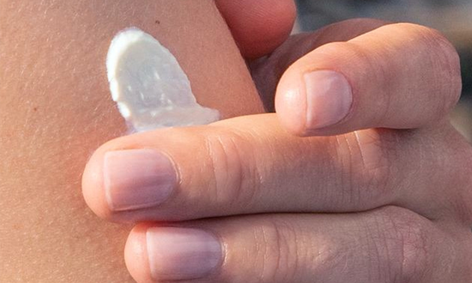 Primo piano di una mano che applica crema sull'avambraccio