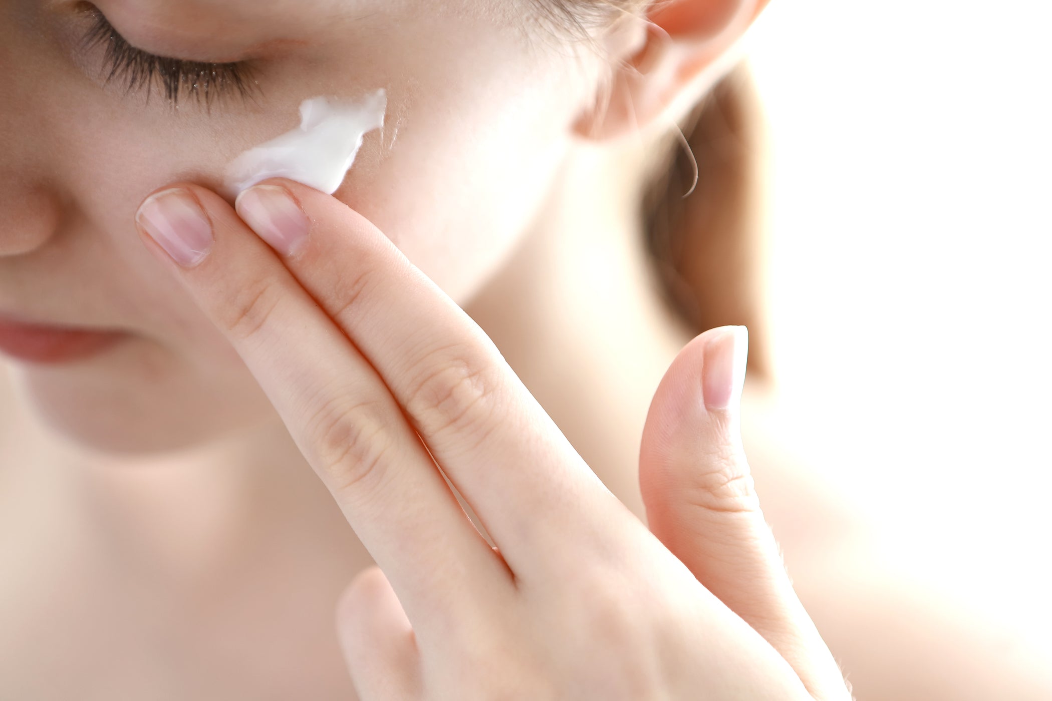 Primo piano: donna applica crema viso sotto l'occhio
