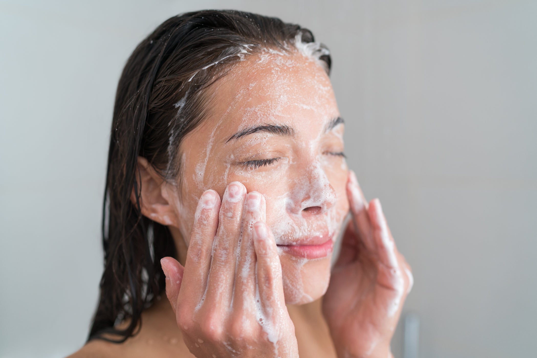 Donna si lava il viso con un detergente