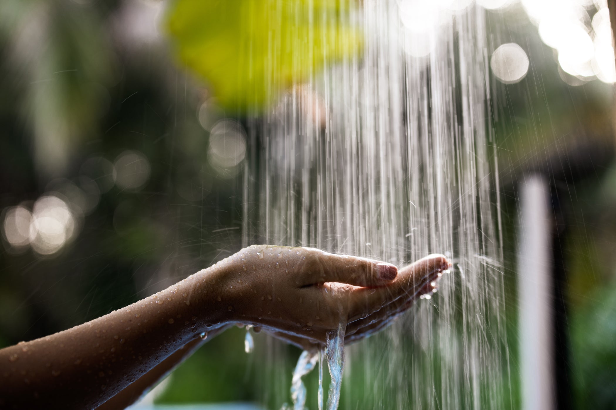 Due mani sotto l'acqua corrente di una doccia – con sfondo sfocato