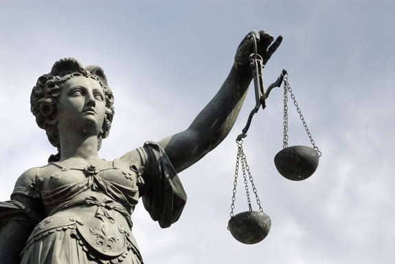 Statua della Giustizia con bilancia davanti al cielo