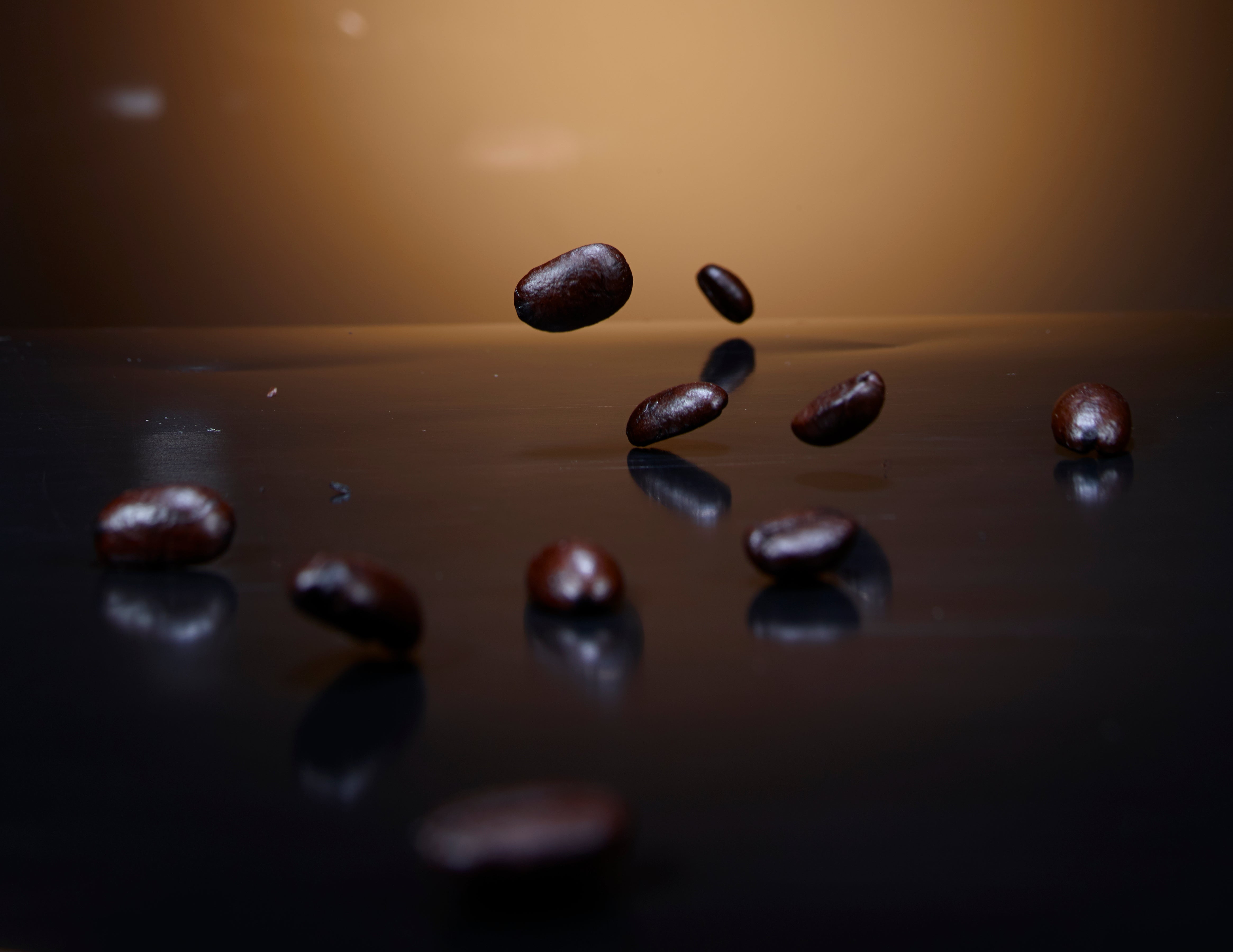 Chicchi di caffè che cadono su superficie scura