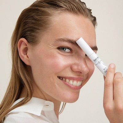 Donna sorridente tiene matita make-up lavera al sopracciglio, primo piano