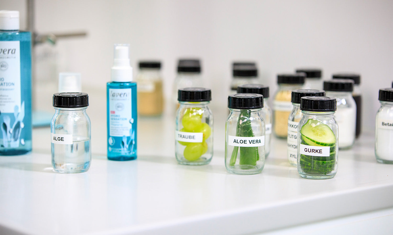 Diversi ingredienti come cetriolo e aloe vera in piccoli vasetti in laboratorio