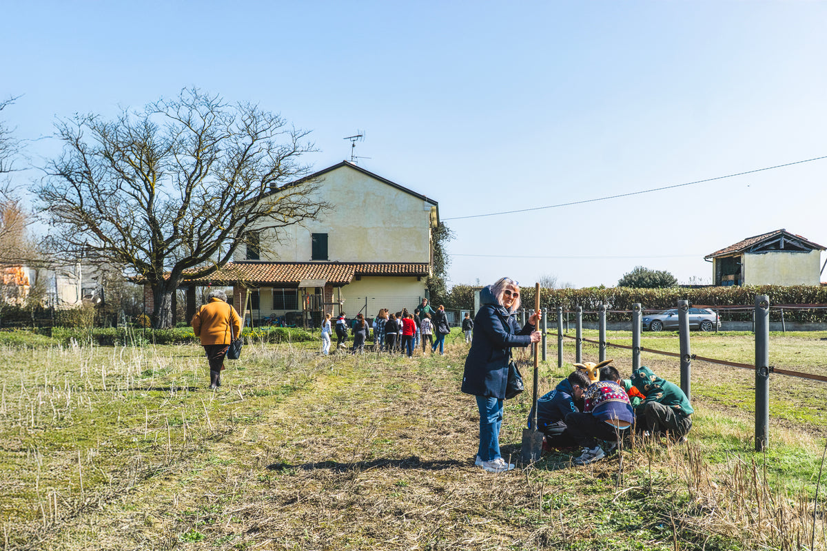 Diverse persone piantano alberi davanti a una casa con cielo blu