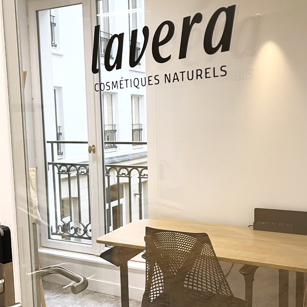 ufficio lavera: scritta "Cosmétiques Naturels" su parete di vetro, scrivania alla finestra