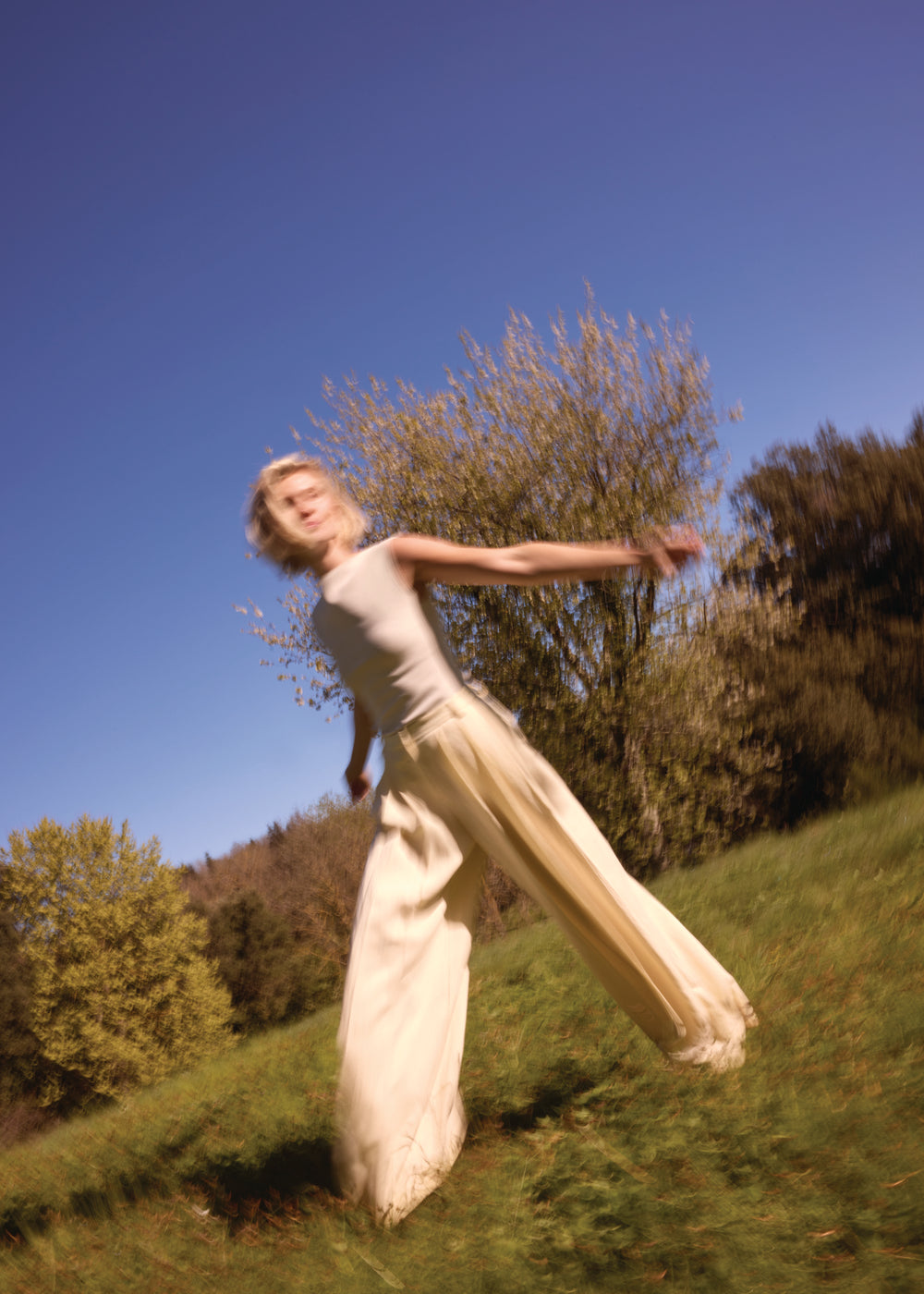 Donna in abito beige gira con braccia aperte nella natura – espressione di gioia di vivere ed equilibrio interiore