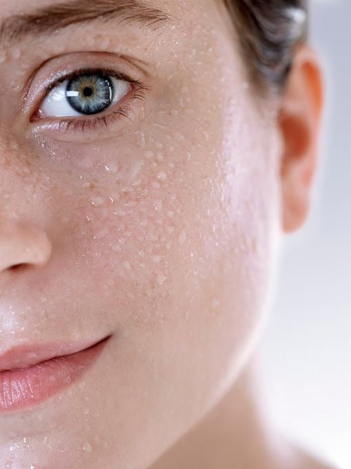 Primo piano: viso con gocce d'acqua sulla pelle, luminosità fresca