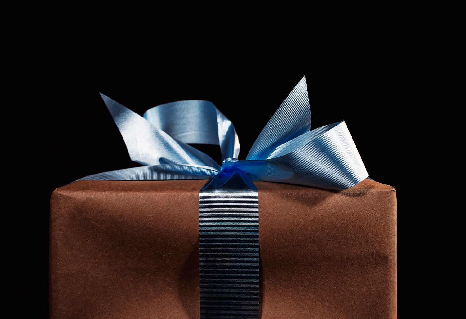 Regalo in carta marrone con fiocco blu su sfondo nero