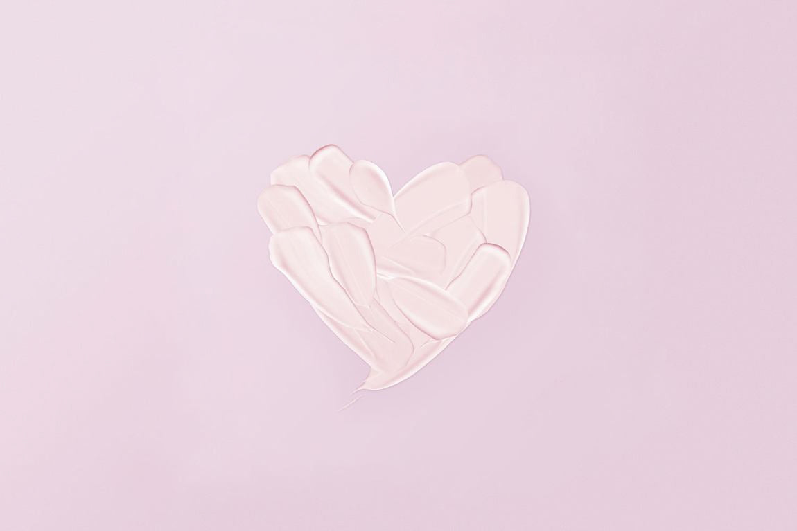 Herzform aus Creme-Textur auf rosa Hintergrund