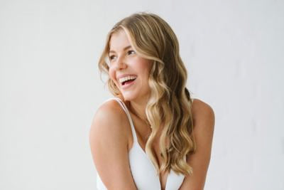 Donna sorridente con lunghi capelli biondi su sfondo chiaro
