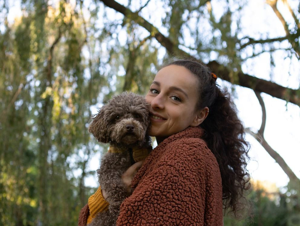 Donna abbraccia cagnolino nel verde e sorride