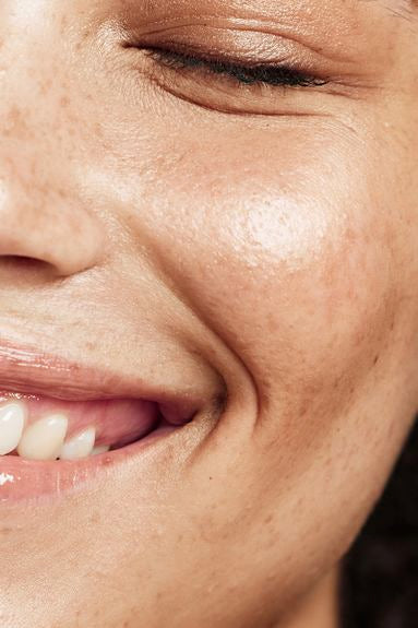 Primo piano di un viso sorridente con texture naturale della pelle