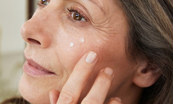 Donna matura applica un punto di crema sotto l'occhio