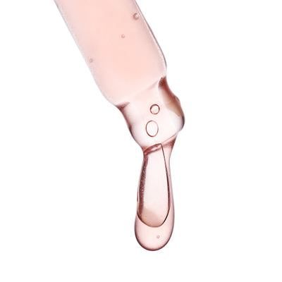 primo piano pipetta con liquido rosa chiaro e goccia su sfondo bianco