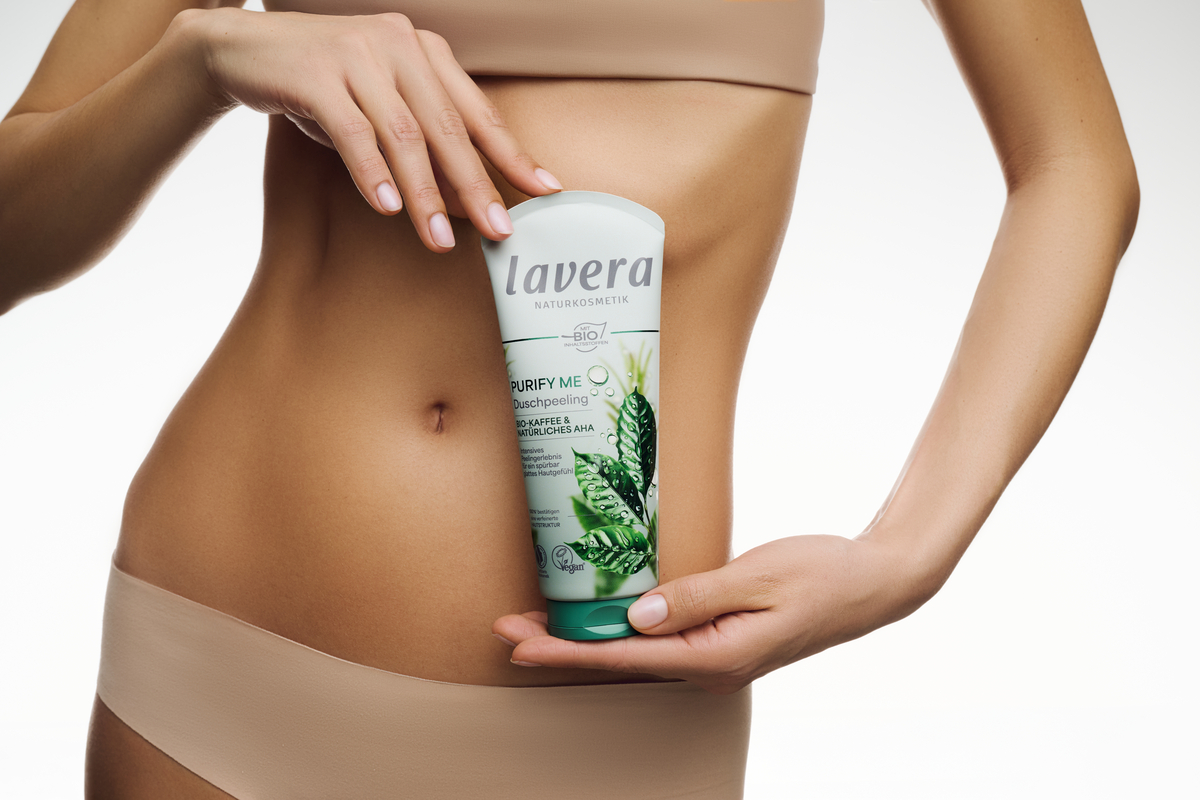 Frau hält Purify Me Duschpeeling vor ihrem Bauch